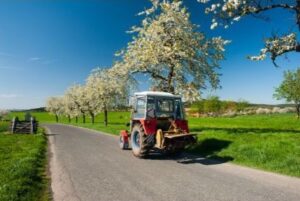 Red tractor on a country road on a spring day - spring agricultural products - universal tractor oils
